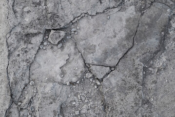 Old white and gray cement road with natural cracks and stones