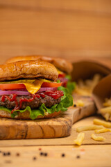 Burger with free. Fast food. Cheese, onion, tomato, ketchup, green salad, meat. Tasty food. Wooden background. Light photo. Restaurant meal. Cooking for yourself. Menu for every day.