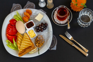 Traditional Turkish Breakfast Plate with boiled egg,orange juice and tea on black surface.Top view