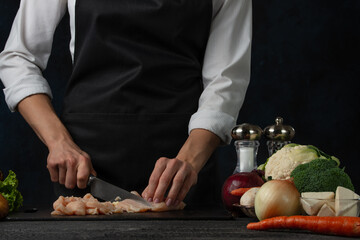 Professional cook cooking tasty meal. Vegetables on the table. Healthy food for you. Girls hands with knife. Meat for meal. Dark background.