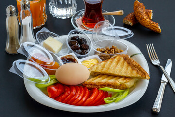 Traditional Turkish Breakfast Plate with boiled egg,orange juice and tea on black surface.Top view