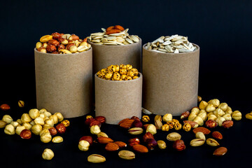 Mixed shelled nuts and unshelled nuts in cardboard boxes on the black background.