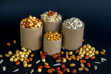 Mixed shelled nuts and unshelled nuts in cardboard boxes on the black background.