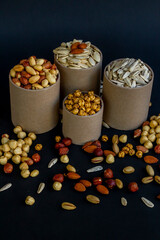 Mixed shelled nuts and unshelled nuts in cardboard boxes on the black background.