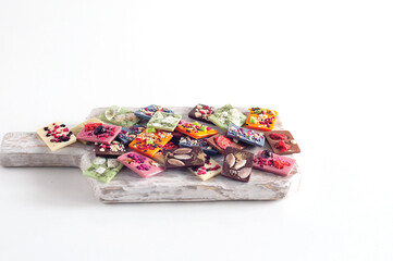 Fototapeta na wymiar Natural Belgian chocolate of different flavors, made from organic products, matcha tea, green, blue, coconut, sprinkled with fruit chips, nuts, seeds.