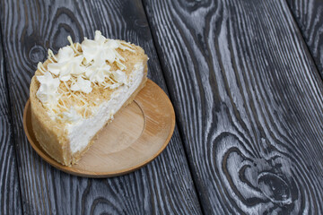 Cheesecake with white chocolate. The filling is visible on the cut. On pine planks painted black and white.