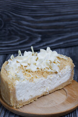 Cheesecake with white chocolate. The filling is visible on the cut. On pine planks painted black and white.