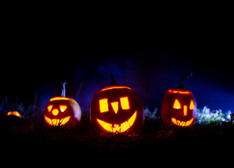 Iluminated horror pumpkins over blue  background with smoke. Halloween banner with copy space.