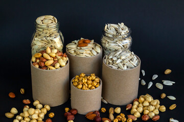Mixed shelled nuts and unshelled nuts in cardboard boxes on the black background.
