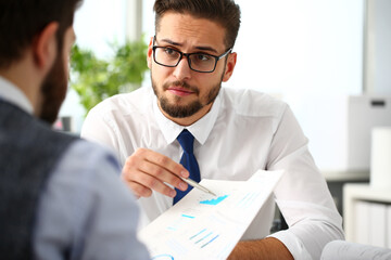 Group of businessmen with financial graph and silver pen in arm solve and discuss problem with...