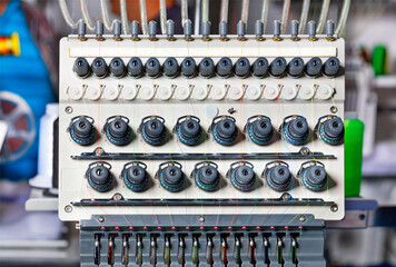 A thread tension control unit at an industrial embroidery machine with multicolored threads,...