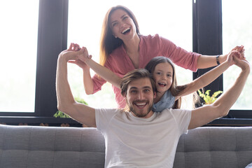 Happy cheerful parents having fun with cute children daughters cuddling playing on sofa together,...