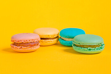 Sweet almond colorful unicorn pink blue yellow green macaron or macaroon dessert cake isolated on trendy yellow modern fashion background. French sweet cookie. Minimal food bakery concept Copy space