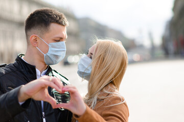 Young couple in love in protective medical mask on face outdoor at street.