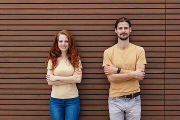 Happy relaxed young couple posing with folded arms