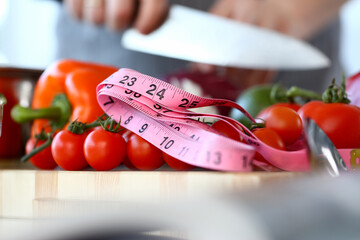Organic Small Cherry Tomatoes Size Measurement. Fresh and Ripe Vegetables. Measuring of Culinary Ingredient with Pink Centimeter. Cooking with Sharp Knife Partial View Horizontal Photography