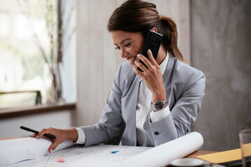 Beautiful businesswoman working on projects. Young businesswoman talking to the phone while working..