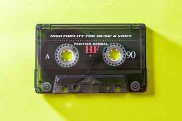 Top view of audio cassette with tangled tape on bright yellow background with copy space.