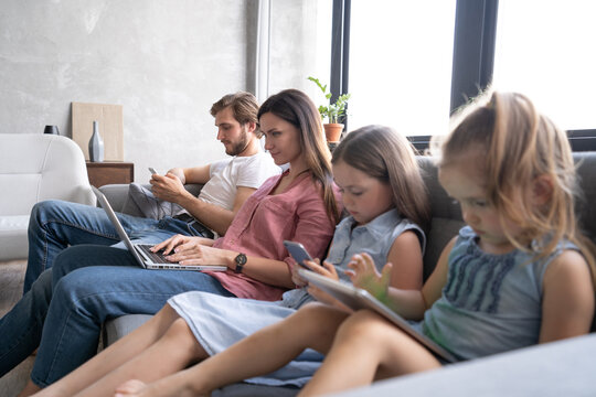 Modern Family Values. Father, Mother And Daughters Using Electronic Devices.