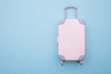 Mini travel luggage suitcase on blue background. Travel, beach, vacation concept.