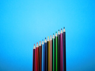 Buntstifte in Reihe in vielen Farben auf blauem Hintergrund