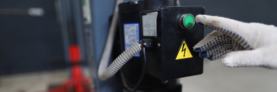 Close-up View Of Persons Hand Pressing Green Button Of Mechanic Lift. Sign Lightning As Symbol For Danger. Technology And Service Station Concept. Car Center