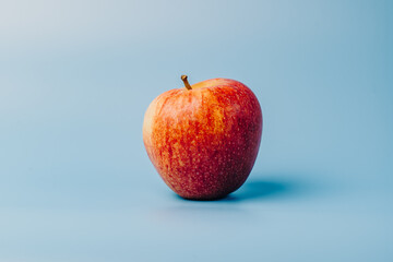 A red apple on a blue studio background