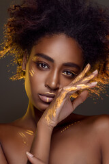 Beautiful african woman with natural make-up with gold sparkles on her face and body. Ethnic makeup. Fashion and Style - obrazy, fototapety, plakaty