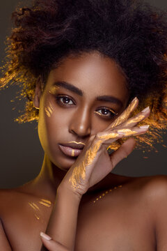 Beautiful african woman with natural make-up with gold sparkles on her face and body. Ethnic makeup. Fashion and Style