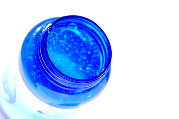 Transparent gel for moisturizing the skin in a plastic blue jar on a white background.