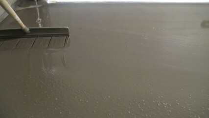 The worker stands in fresh mortar, cementing and leveling the floor. Bricklayer smooth out the...