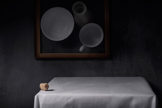 Still life with a shell on a table covered with a white tablecloth.