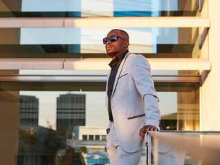 African-American man in a fancy suit enjoying the sunset outside the office.