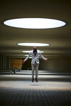 African-American businessman lit by a skylight jumping
