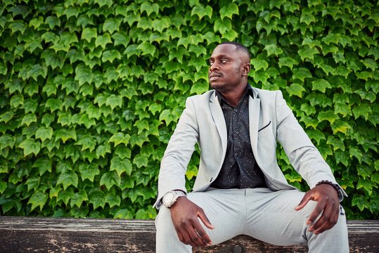 African American man sitting on a park bench.