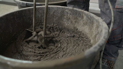 The mortar is mixed in a bucket. Floor repair. Mixing of building floor mortar. mixing cement in the bucket mixer with the trowel at the side work, Construction work