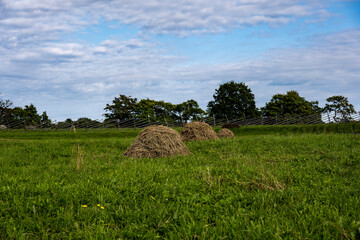 vintage wooden mill behind a fence on a green hill against a blue sky background