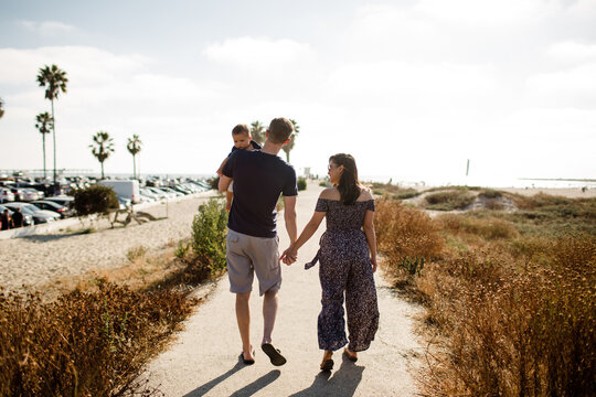 Parents Holding Hands Walking Alongside Sand Dunes with Son