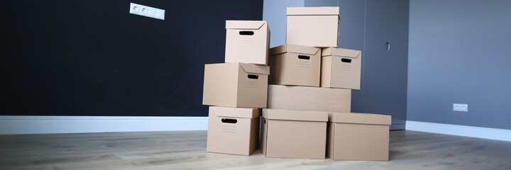Close-up of unpacked cardboard boxes. Empty room with personal stuff packed in carton. Purchased apartment or house property. Moving day and renovation concept