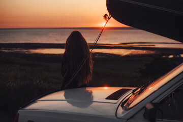 Longhaired girl watches sunset at the river.