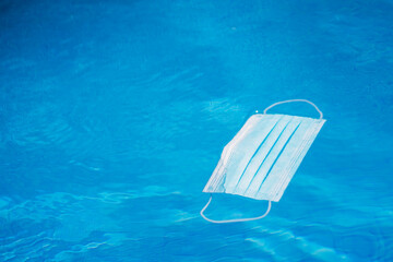 Mask floating on pool water during Covid pandemic.