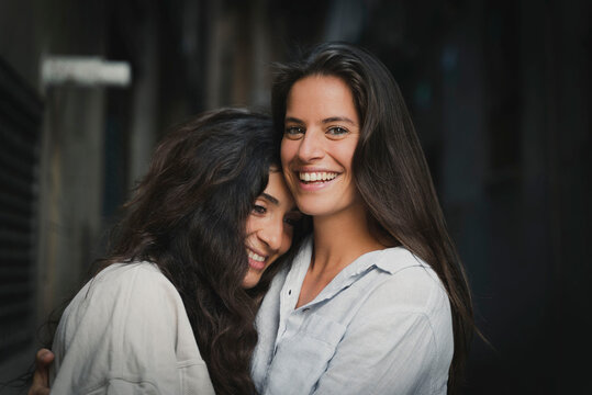 Lesbian girls couple hug each other. Girl looks at camera.