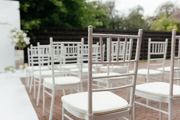 Place for guests at the wedding ceremony. Outside ceremony. White chairs