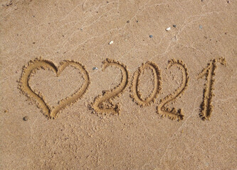 The concept of a New year. Heart and numbers 2021 in the sand. Summer beach holidays . The message is handwritten