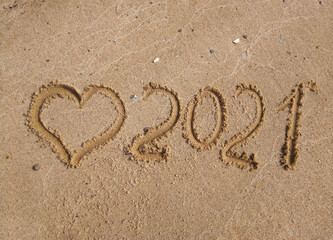 The concept of a New year. Heart and numbers 2021 in the sand. Summer beach holidays . The message...
