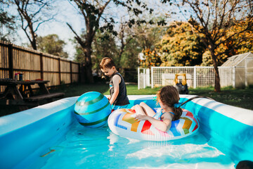 Two preschool age kids swimming in backyard pool