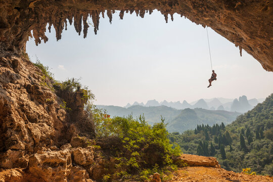 Man climbing on arch at Odin's Den next to Moon hill in Yangshuo, China