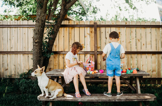 Young brother and sister looking through easter eggs outside