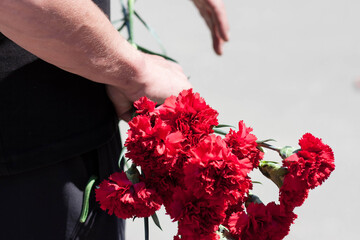 Carnation flowers in the hands of a man on Victory Day
