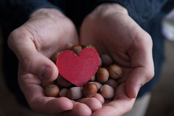 A man holding a handful of nuts and cardboard heart